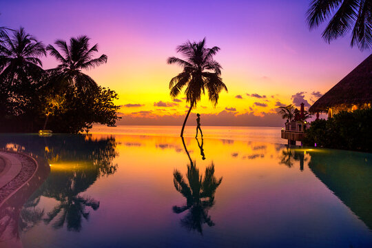 Sunset on Maldives island. Beautiful sky and ocean and beach with palms background for summer vacation holiday and travel concept.
