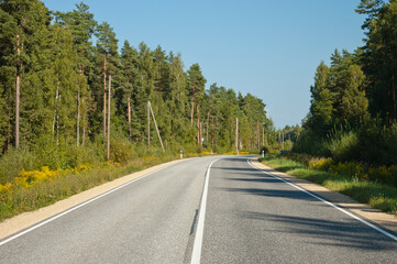 Fototapeta premium a highway, in the photo a road in the forest against a blue sky background