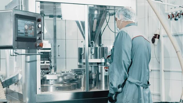 4K Machine operator working on pharmaceutical production line. Automatic Capsule Filling Machine. Automatic production line at a pharmaceutical company. Preparation and production of tablets close-up