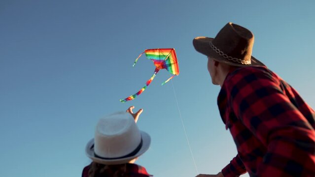 Happy family. People in park launch flying kite. Family in grass at sunset are playing together. Son, daughter and parents launch kite in wind. Happy family concept. Kite soars in the wind in the sky