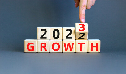 Planning 2023 growth new year symbol. Businessman turns a wooden cube and changes words Growth 2022 to Growth 2023. Beautiful grey background, copy space. Business 2023 growth new year concept.