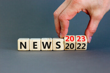 2023 News new year symbol. Businessman turns a wooden cube and changes words News 2022 to News 2023. Beautiful grey table grey background, copy space. Business 2022 news new year concept.