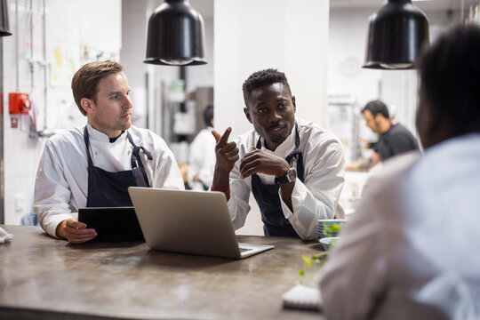 Multiracial chefs planning business strategy in restaurant kitchen