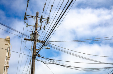 Overhead power cables on a street in San Francisco, California seen against a blue sky with clouds.