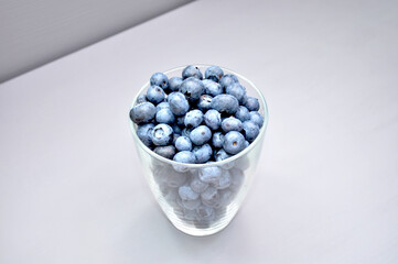 blueberries in a transparent glass on a gray-blue background