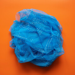 Fototapeta premium Crumpled transparent blue scarf on red background. Top view.