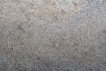 Level grey concrete texture riddled with black small grains