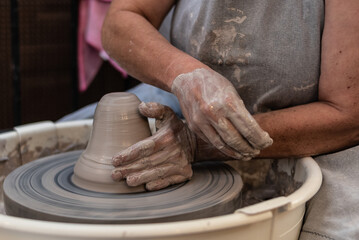 hands working a piece of clay on the potter's wheel