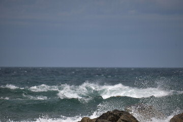 Küstenlinie mit Felsen aus rosa Granit in der Bretagne mit blauem Himmel und Meer mit Wellen