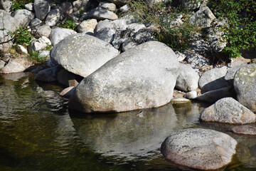 Naklejka na ściany i meble Große Felsen und kleine Steine liegen in einem Fluss und bilden einen kleinen See