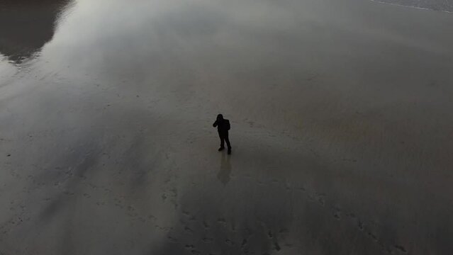 A person walking on the sand on the picturesque beach of Kvalvika, Moskenesoy, Lofoten Islands, Norway.