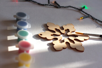 Closeup of a wooden Christmas, New year decoration (snowflake), the brush, paints and a colorful garland. Winter holidays preparation. Creativity, hobby, DIY concept background