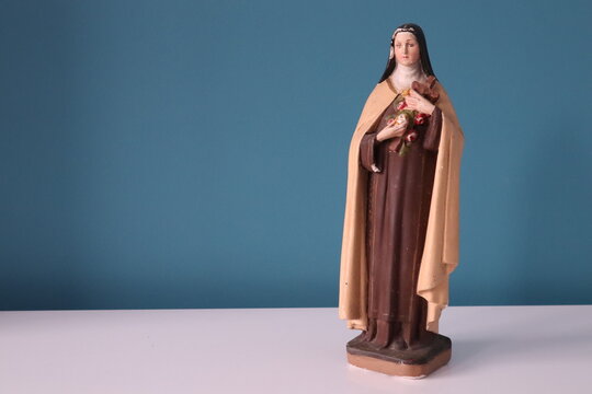Small old statue from woman with a cross and roses in het hands