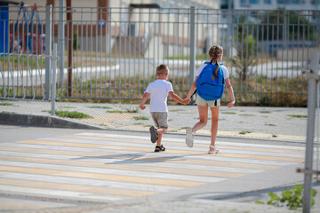 Brother and sister run across a pedestrian crossing. Children Run along the road to kindergarten and school.Zebra traffic walk way in the city. Concept pedestrians passing a crosswalk