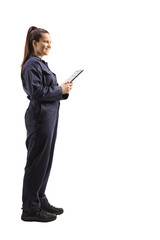Full length profile shot of a female auto mechanic worker standing and holding a clipboard