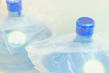 A top view of two plastic gallon water bottle containers with white labels stands on a blue background. Clean. Clear. Closed. Container. Cooler. Couple. Delivery. Dispenser. Distilled. Drink. Empty