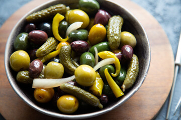 Close up of pickled gherkins, chilli peppers and olives in a bowl