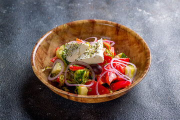 Greek salad with feta and vegetables on stone table