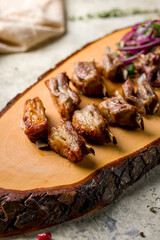 Kebab from lamb ribs on the board with red onion on stone table, vertical