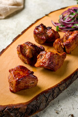 Kebab of pork with red onion on the board on stone table, macro close up, vertical