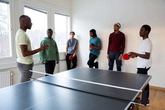Instructor giving table tennis training to students in games room
