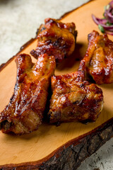 skewers of pork ribs with red onion on the board on stone table, macro close up, vertical