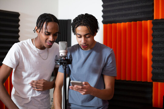 Teenage Rappers Sharing Smart Phone While Recording Song In Studio