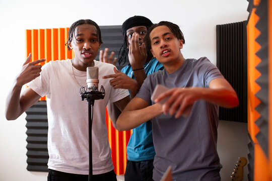 Portrait of teenage rappers gesturing while recording song in studio