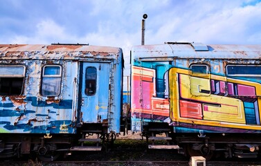 Vertical shot of a Rusty abandoned train with colorful graffiti in Cluj, Romania