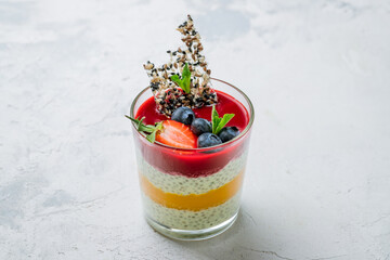 Chia pudding with mango and berries , strawberry,blueberry and mint on white concrete table
