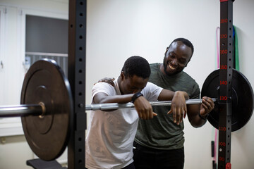 Smiling male instructor motivating athlete during workout in gym