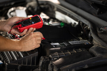 Mechanic doing car inspection, he is testing car battery with tester. Check battery voltage with...