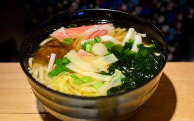 Japanese seafood ramen with seaweed, bamboo shoots and mushrooms placed on restaurant's table.