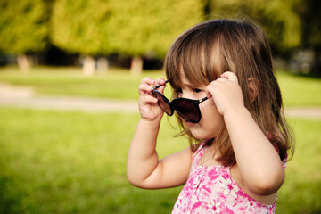 Little girl wearing mom's sunglasses. Portrait of a sweet baby girl who's stolen mom's sunglasses and happy to wear them trying to look like a grown up.