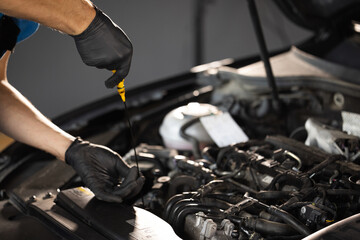 Close-up of automotive mechanic checks the oil level on the car engine dipstick. Car oil quality....