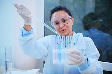 Confident African American pharmacologist, medical biologist, laboratory assistant using lab...