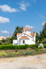 A small white church with an orange roof. Crosses on the roof and a cemetery by the church. Paphos, Cyprus.
