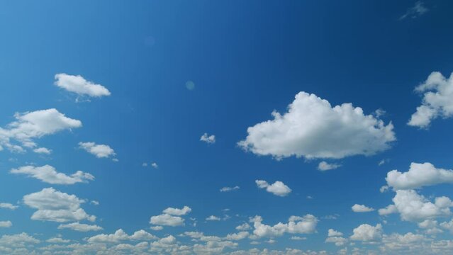 Clouds formation running across the blue sky. White puffy and fluffy layered clouds on blue sky. Time lapse.