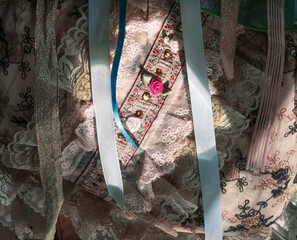 Fabric material and trims with a spotlight on sequins and cloth roses. Lace , ribbons, and embroidery surround the central design.