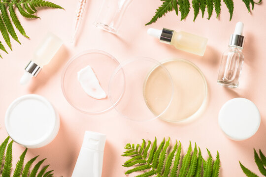 Cosmetic laboratory concept . Glass petri dish with cosmetic products and green plants. Flat lay image.