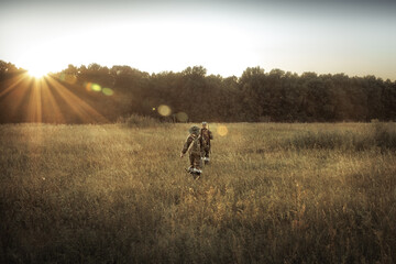 Hunters men hunting in rural field nearby forest at sunset during hunting season