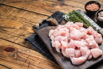 Raw chicken fillet cut into cubes, Uncooked sliced poultry meat, on wooden board. Wooden...