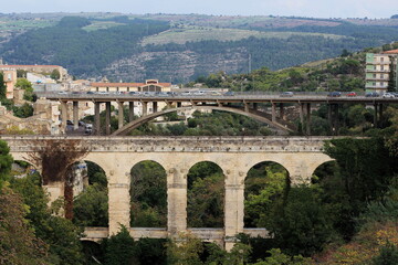 Obraz premium View of the two Ragusa / Sicily bridges, in the foreground the ancient Ponte Vecchio / Ponte dei Cappucini, in the background Ponte Papa Giovanni XXIII, the historic center of Ragusa.