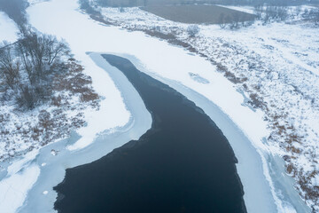 Aerial view of the river covered with ice, thaw, melting ice on the river