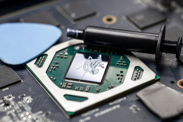 A tube of thermal paste lies near the video card chip, the master changes the thermal paste on the...