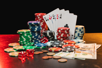 Close up composition of poker chips, dices, playing cards and dollar banknotes on the desk with grunge texture over black background