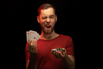 Studio portrait of smiling handsome young bearded manwinking while posing with a fan of playing...