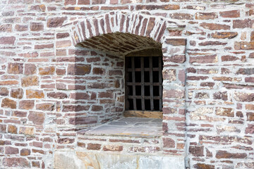Fototapeta na wymiar Loophole in the fortification wall of a medieval castle, outside view