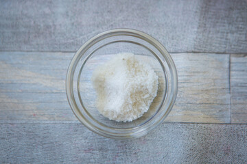 Bowl of salt on gray wooden background, top view