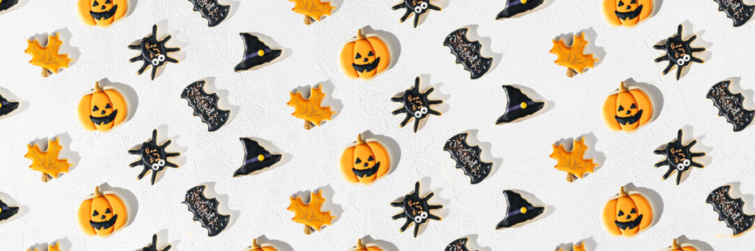 Flat lay pattern of Halloween sugar cookies - pumpkin jack, witch hat, spider in a plate on white background. Long banner